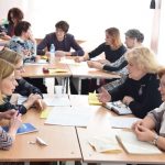 Mokytojai, susėdę prie apskritų stalų aktyviai diskutuoja