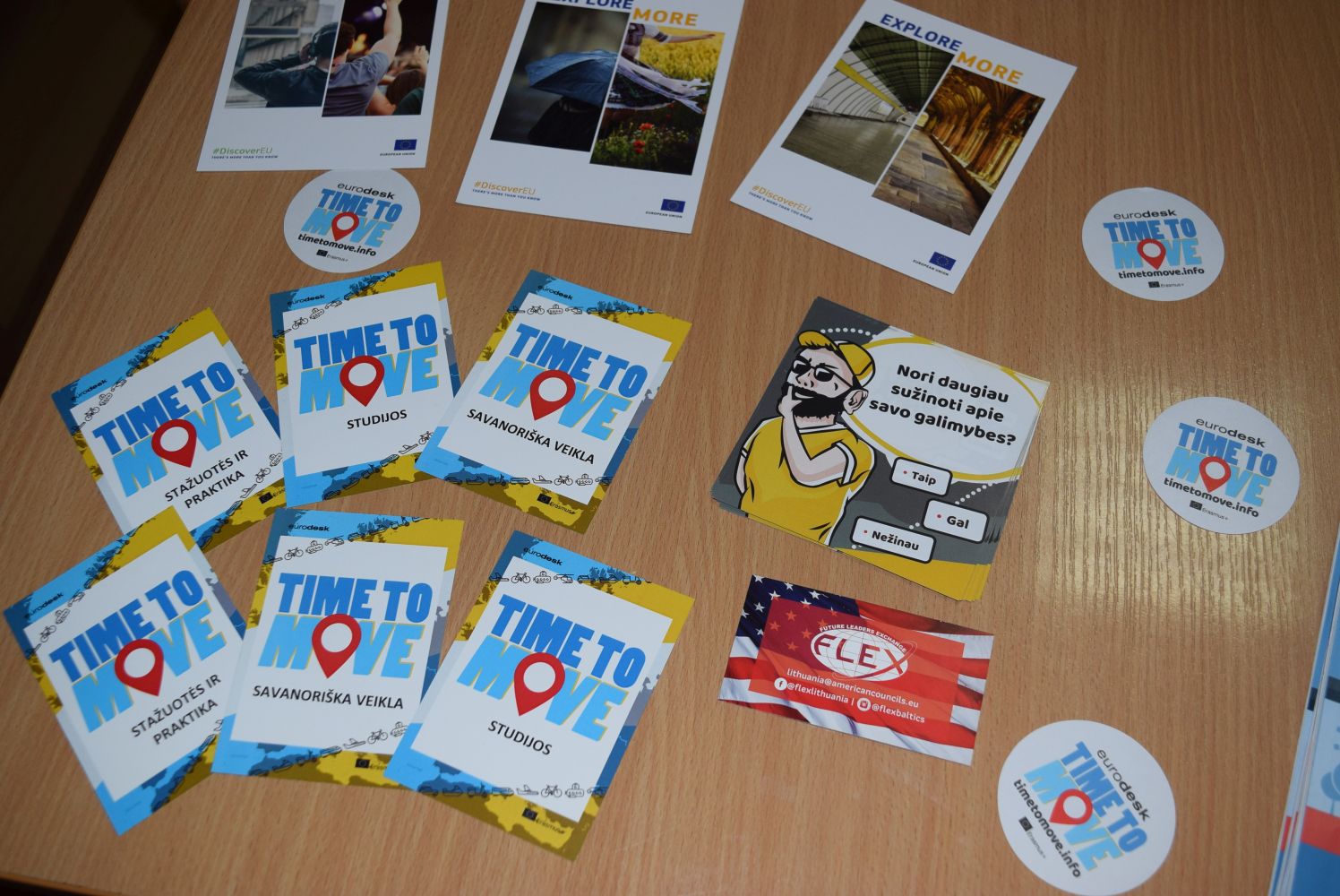 Time To Move kampanijos lankstinukai, išdėlioti ant stalo