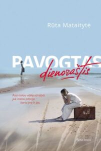 pajūryje moteris sėdi ant lagamino