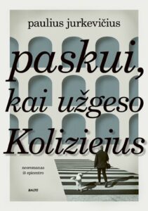 žmogus eina su šuniu per perėją link pastato