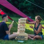 Du jaunuoliai - vaikinas ir mergina, sėdintys ant žodės ir dėliojantys jengos kaladėles ant dėžės su pavadinimu EURODESK