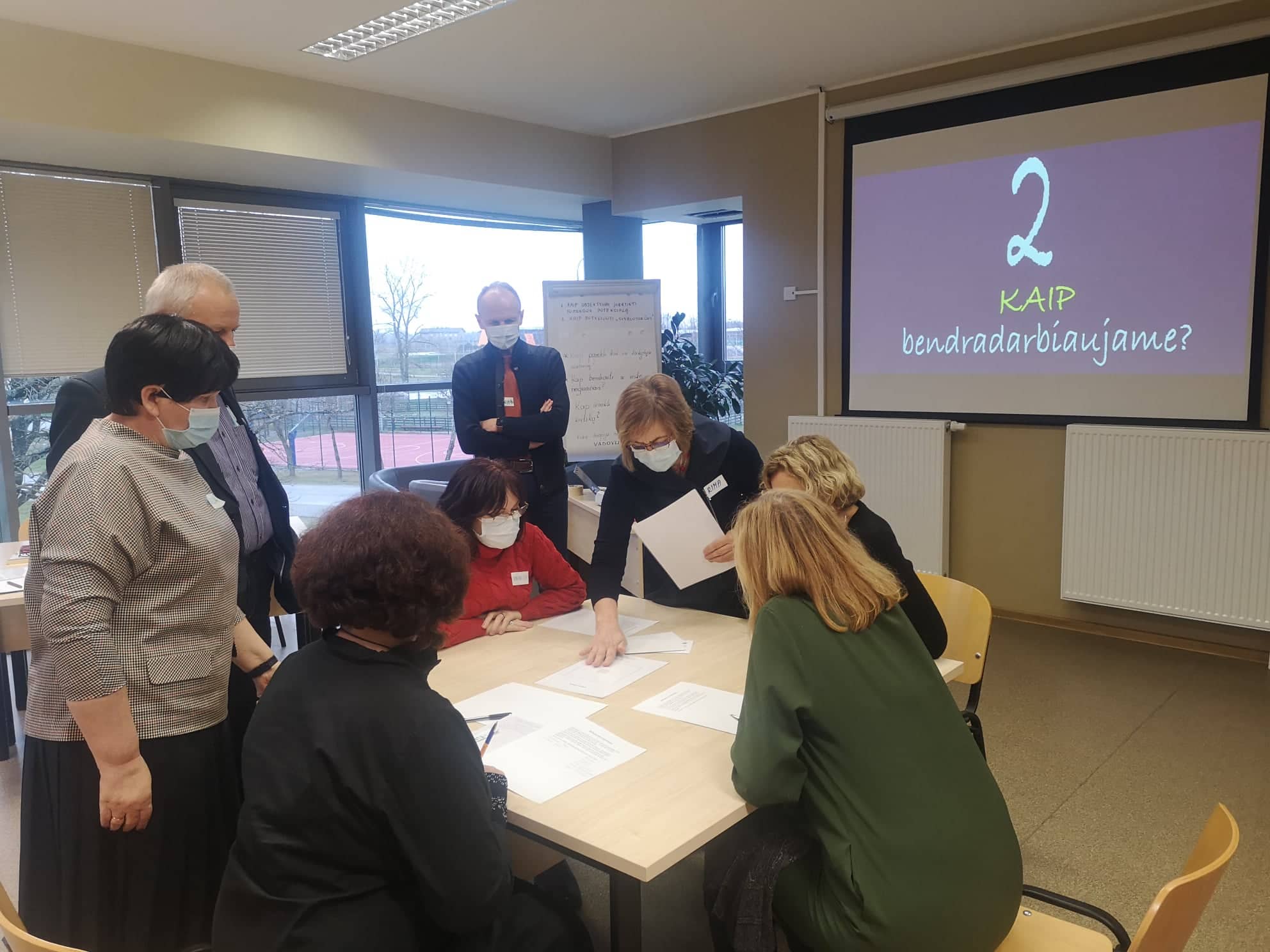 Aplink stalą susėdę diskutuoja mokymų dalyviai 