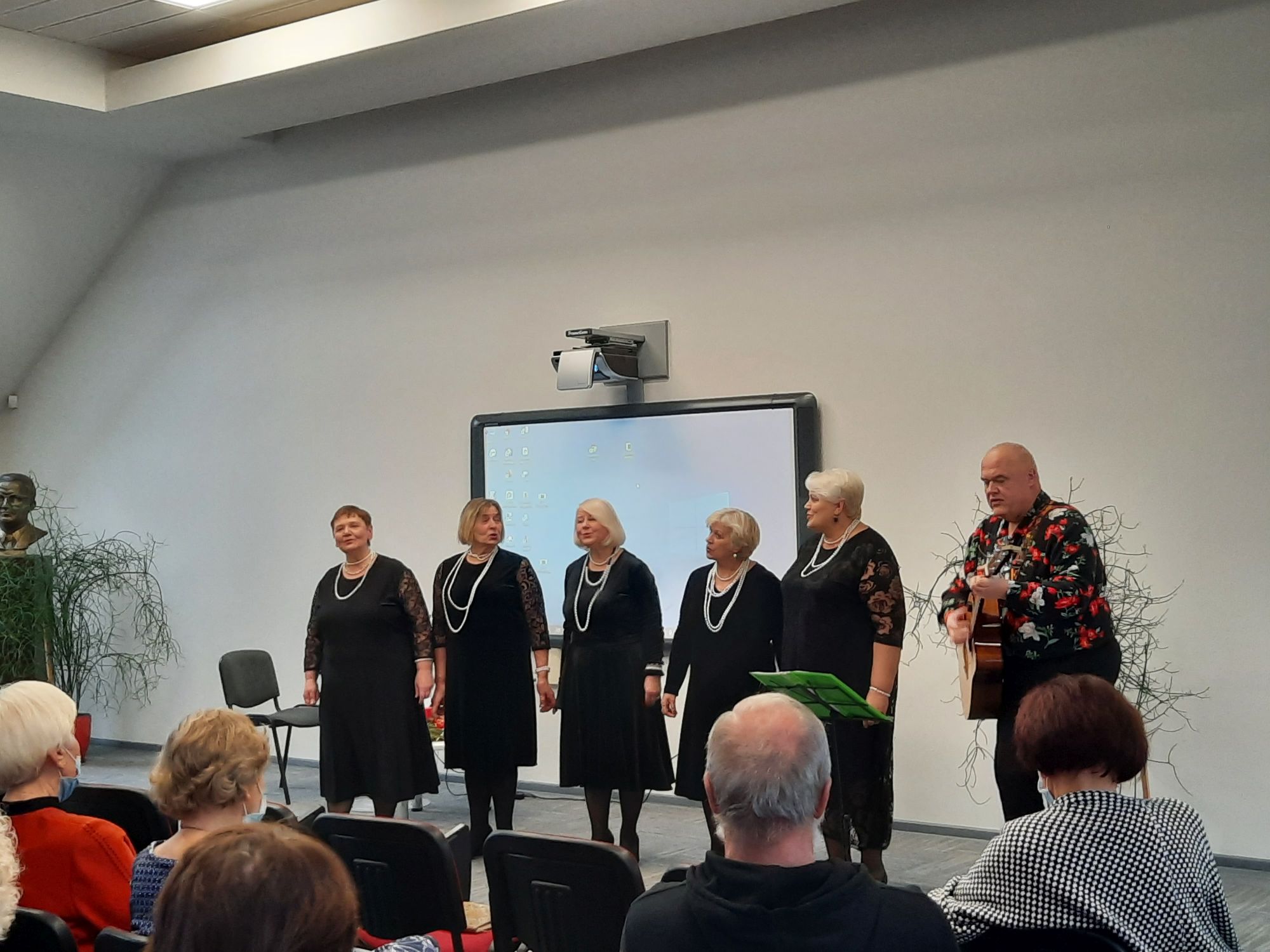 Dainuojančios moterys ir vyras su gitara - Suginčių moterų romantinių dainų ansamblis „Prisiminimai“, vadovaujams V. Gaulės