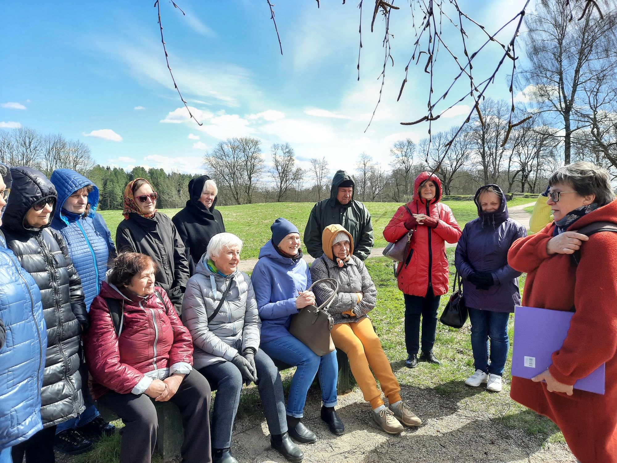 Molėtų TAU dalyvės susėdę klausosi gidės pasakojimo