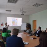 Renginio dalyviai, susėdę klausosi lektorės